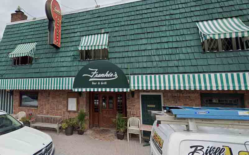 Frankie's Bar & Grill exterior featuring a green shingle roof, striped awnings, and inviting entrance, embodying the cozy atmosphere highlighted in local bar recommendations along the Jersey Shore.
