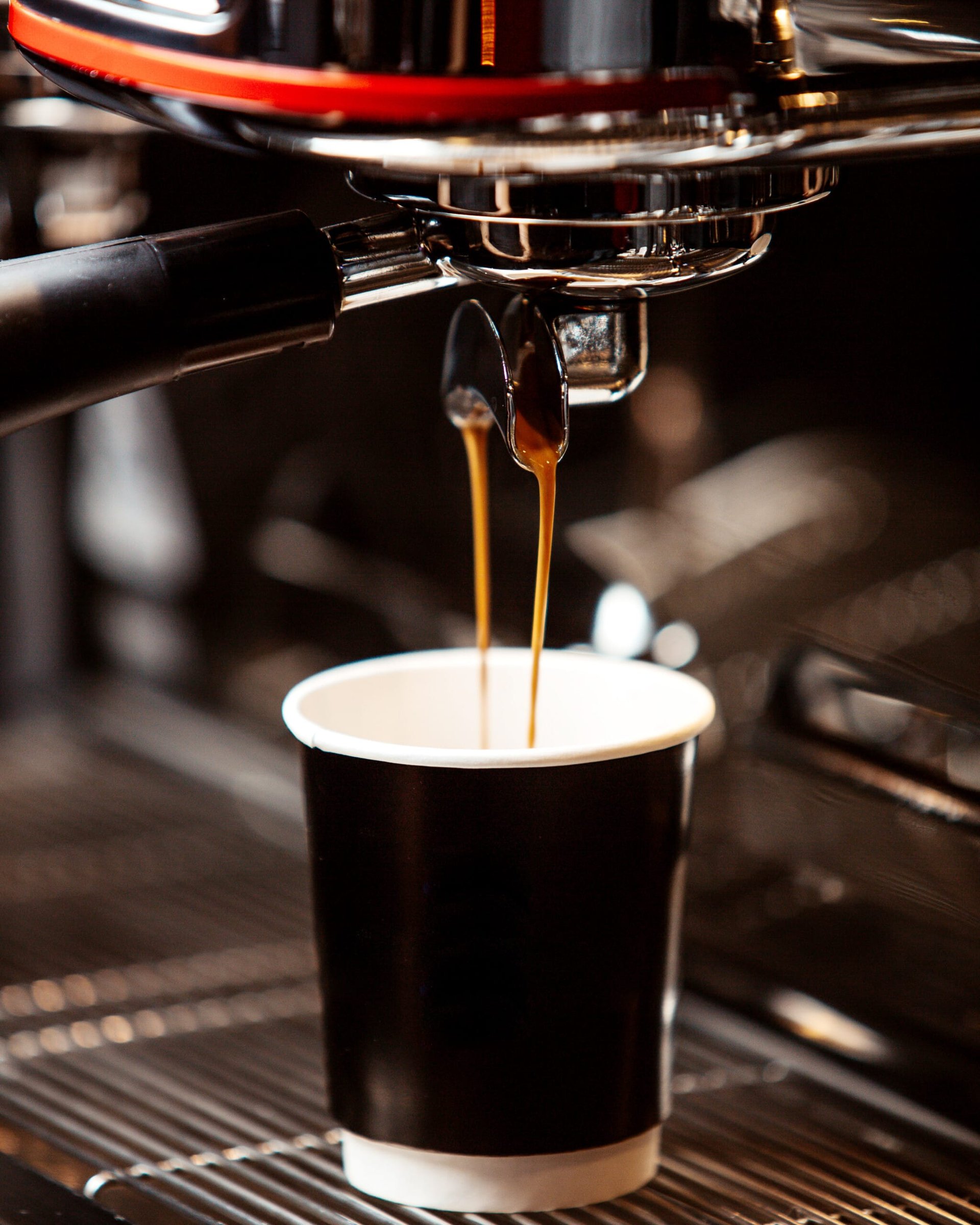 Coffee being poured from an espresso machine into a black disposable cup, highlighting the coffee experience at Jersey Shore coffee shops.