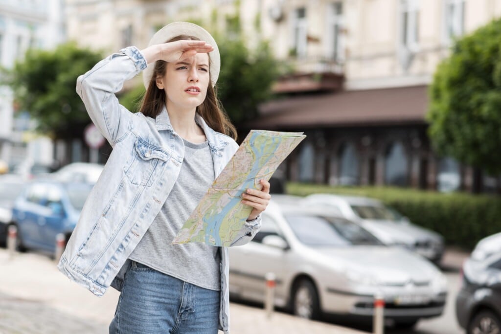 Young woman holding a map and looking away, exploring urban surroundings, symbolizing the importance of location analysis for vacation rental investments.