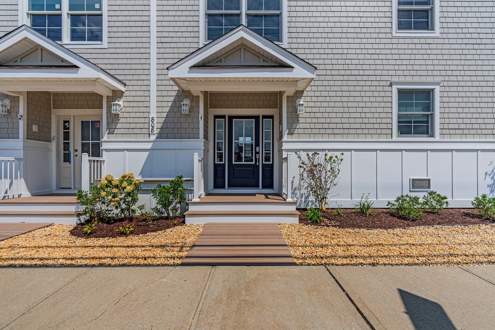 Cozy beach rental exterior in Seaside Heights, featuring modern architecture, welcoming entrance, landscaped garden, and wooden deck, ideal for Polar Bear Plunge participants and winter getaways.