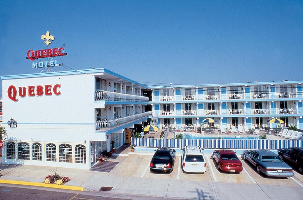 Quebec Motel in Wildwood, featuring mid-century modern architecture, vibrant blue and white exterior, balconies, and a swimming pool area, reflecting the iconic motels of the Jersey Shore's tourism boom.