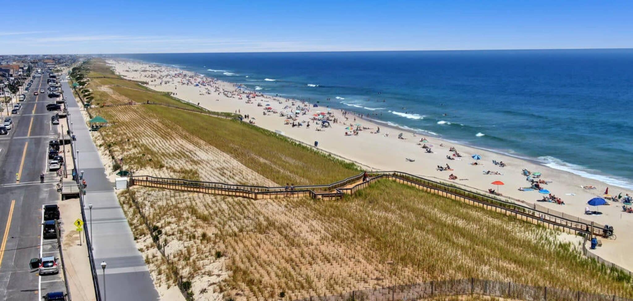 Aerial view of Seaside Park beach with sandy shore, beachgoers, and boardwalk, showcasing proximity to vacation rentals and outdoor amenities.