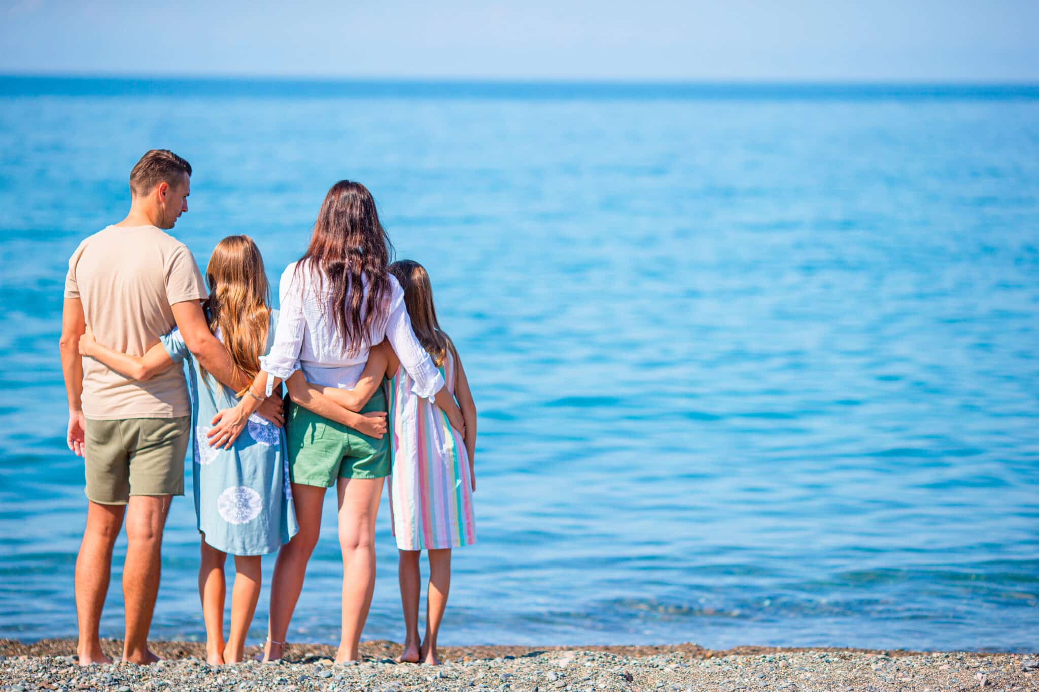 Family enjoying a beach vacation, standing together by the water's edge, with the ocean in the background, embodying the joy of family-friendly experiences at the Jersey Shore.