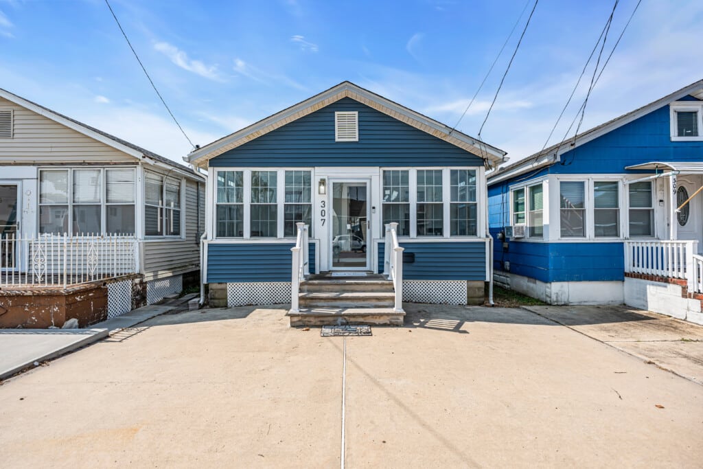 Blue vacation rental property with white trim and steps, flanked by similar houses, ideal for investment and bonus depreciation benefits.
