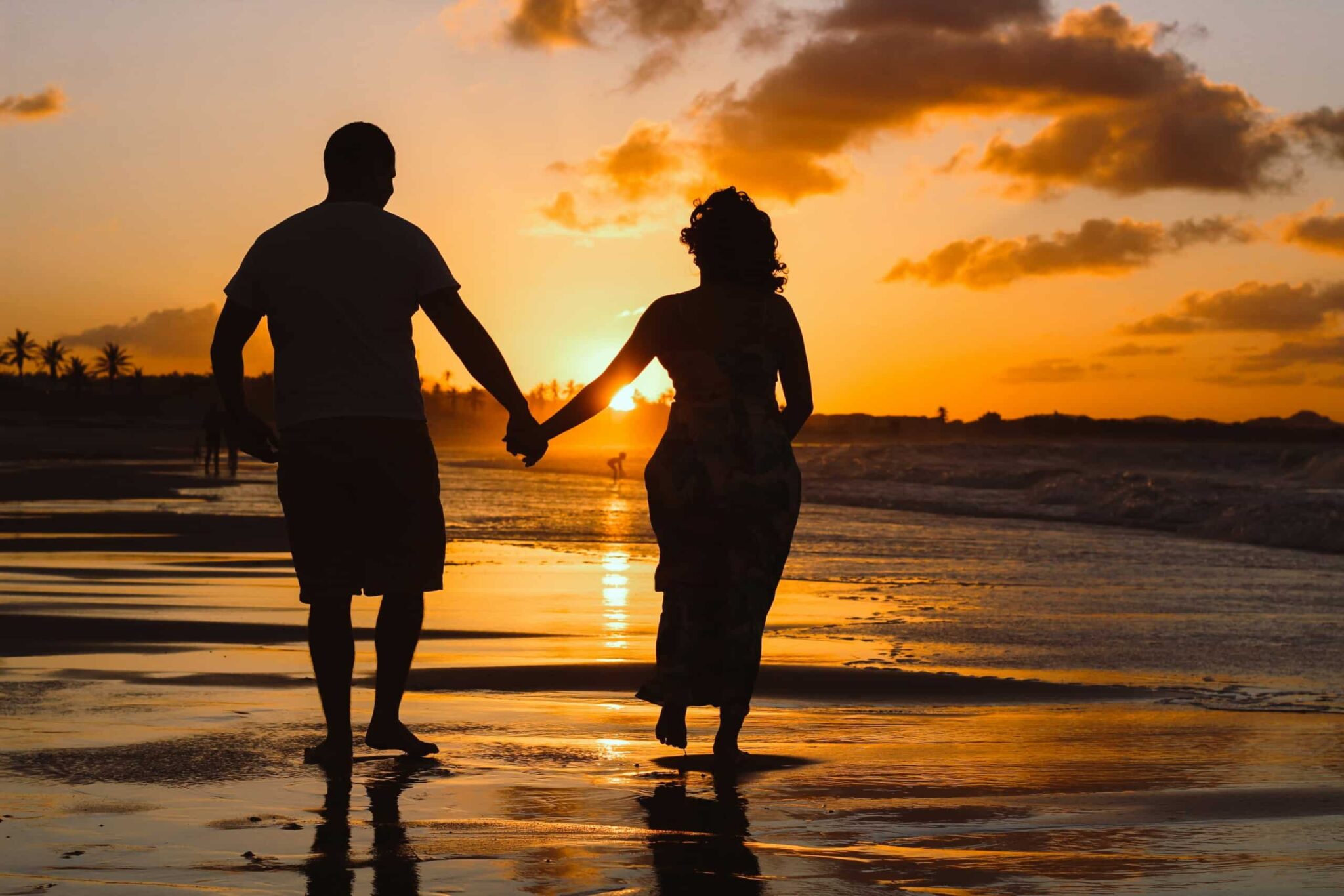 Couple holding hands on a beach at sunset, symbolizing romance and connection, ideal for a romantic getaway in Seaside Heights.