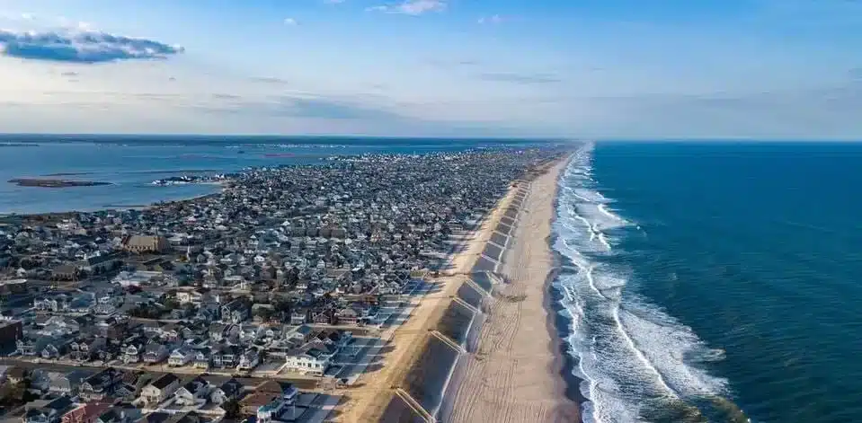 Aerial view of the Jersey Shore coastline featuring sandy beaches, ocean waves, and seaside homes, illustrating a popular vacation destination for families and groups.