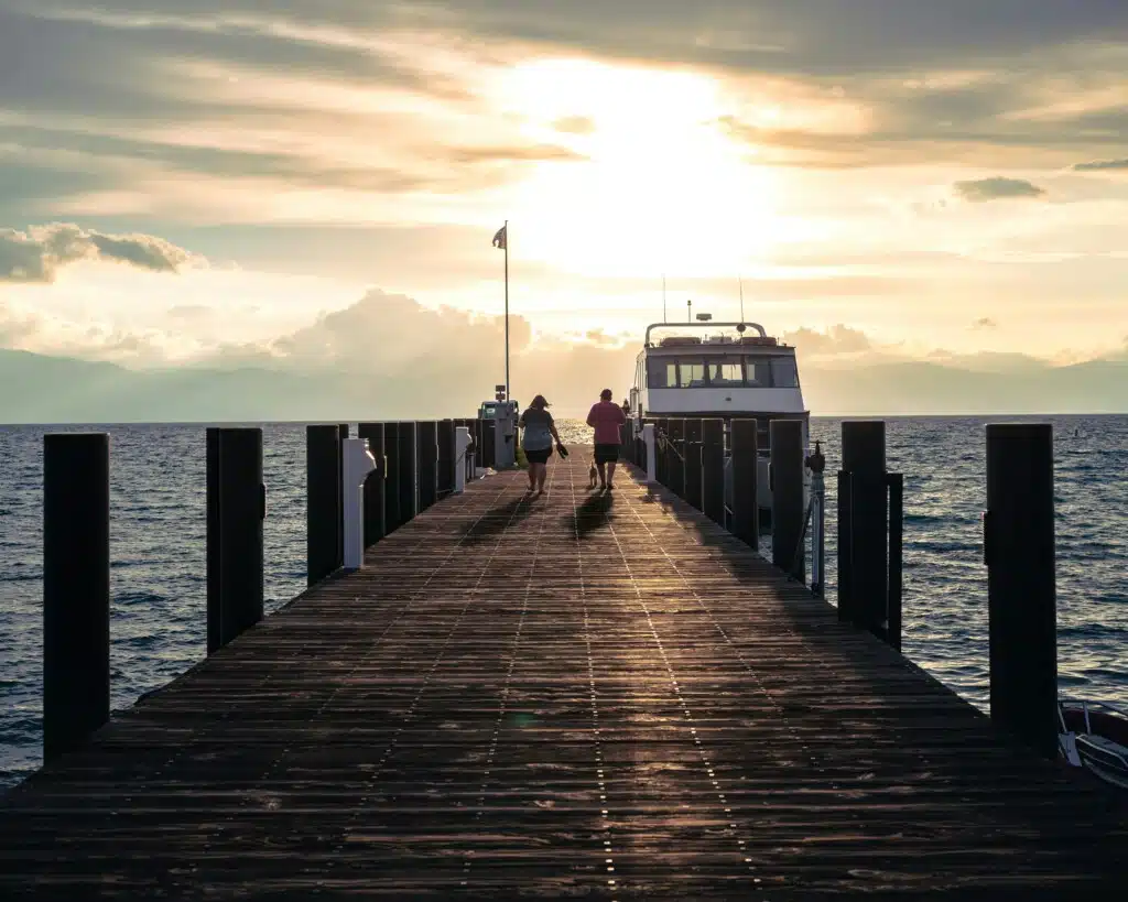 Couple walking hand in hand along a wooden pier at sunset, with a boat docked nearby, embodying a romantic seaside experience in Seaside Heights.