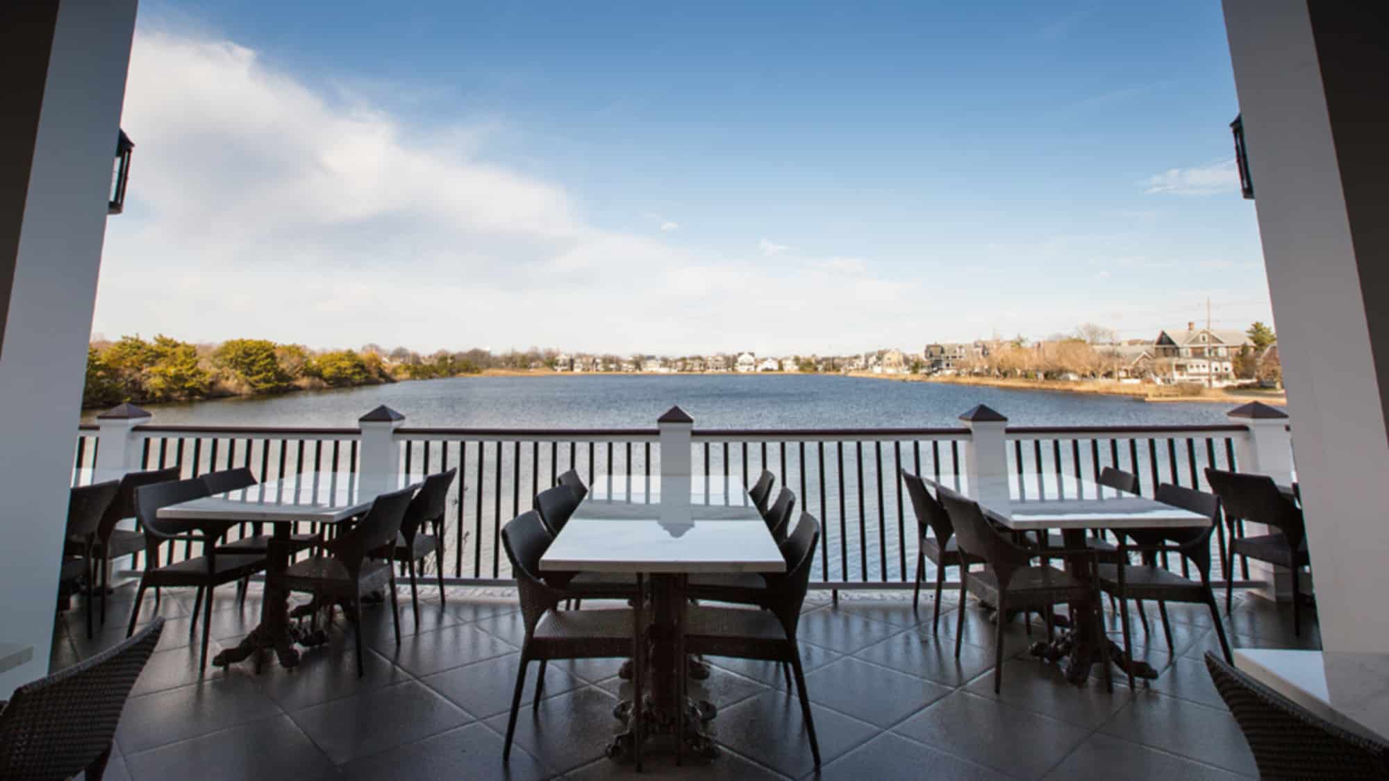 Waterfront dining area with tables overlooking a serene lake, showcasing scenic views and inviting ambiance at the Jersey Shore.