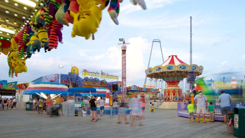 Colorful plush toys hanging from the pier, bustling arcade and amusement rides at Casino Pier, families enjoying the boardwalk atmosphere in Seaside Heights, New Jersey.