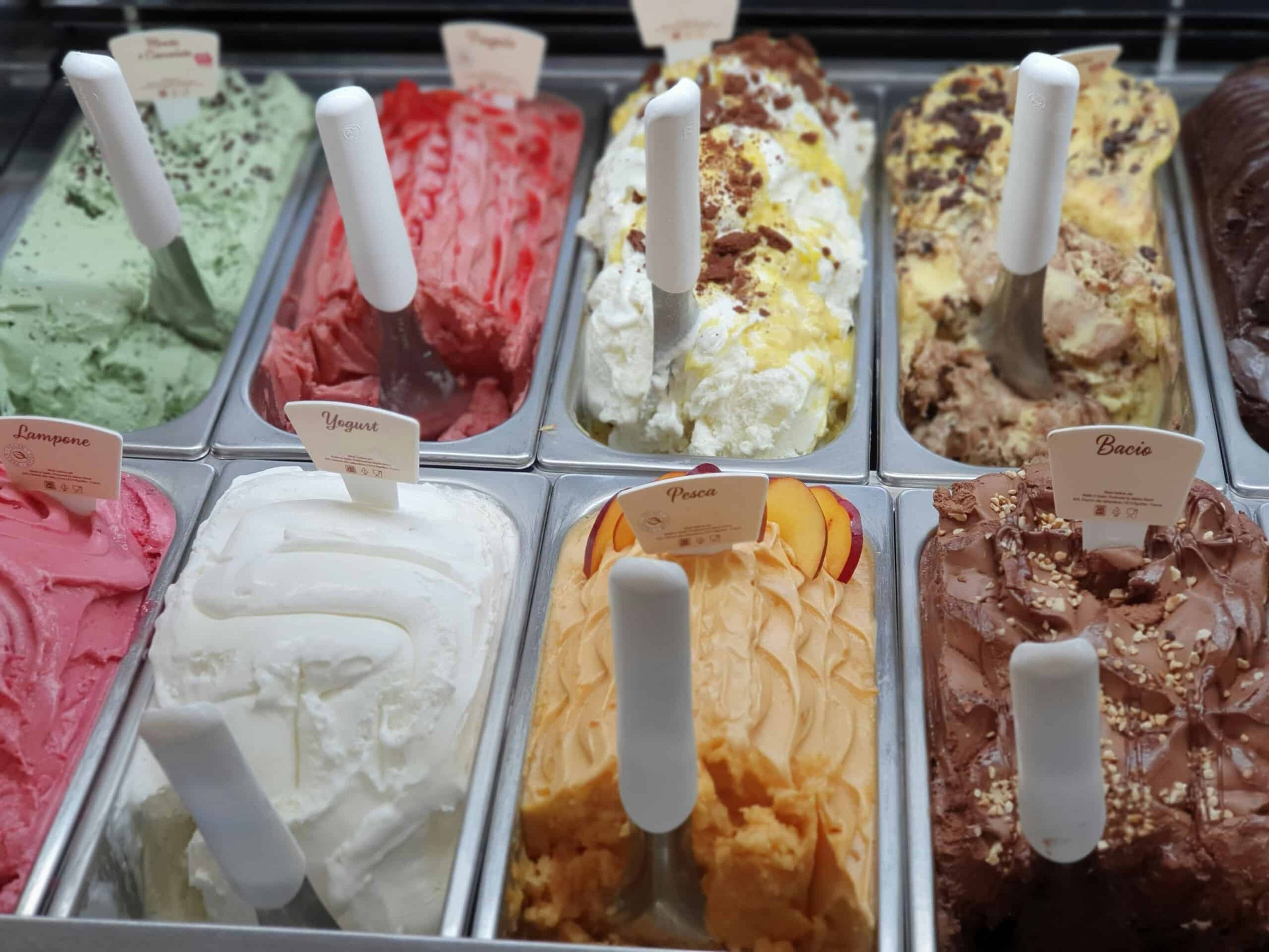 Colorful assortment of gelato flavors in a display case, featuring labels for flavors like Lampone, Yogurt, Pesca, and Bacio, showcasing popular ice cream options at the Jersey Shore.