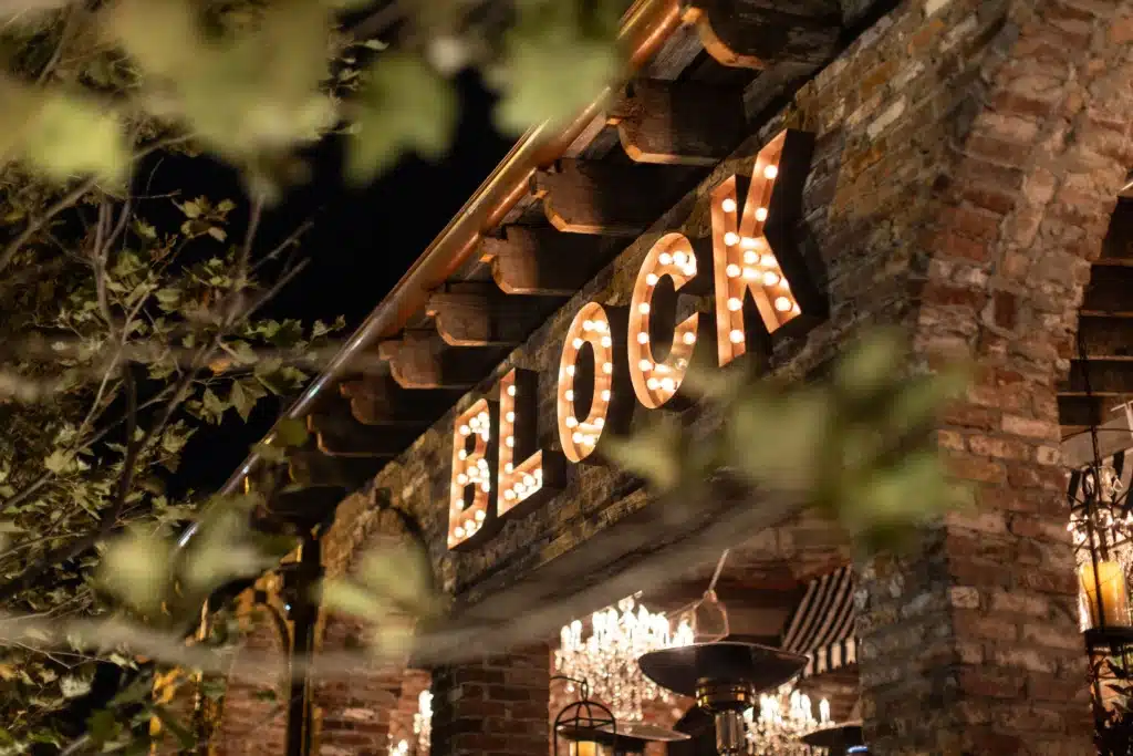 Block restaurant sign illuminated at night, showcasing modern steakhouse ambiance in Long Branch, NJ, with brick architecture and decorative lighting.