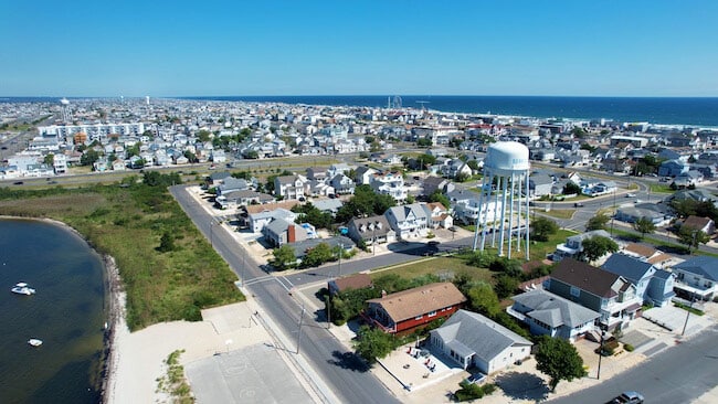 Aerial view of seaside park houses near the Jersey Shore, featuring residential properties, a water tower, and proximity to the beach, highlighting potential vacation rental investment opportunities.