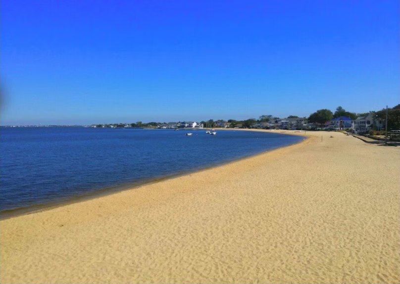 Serene beach view of Ocean Gate, New Jersey, featuring soft sand, calm waters, and nearby waterfront homes, ideal for kayaking and paddleboarding.