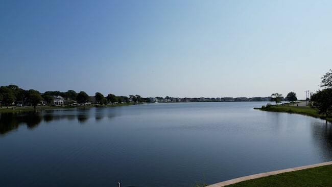 Lake Como waterfront view showcasing tranquil waters, residential homes lining the shore, and lush greenery, reflecting the appeal of family-friendly coastal living.