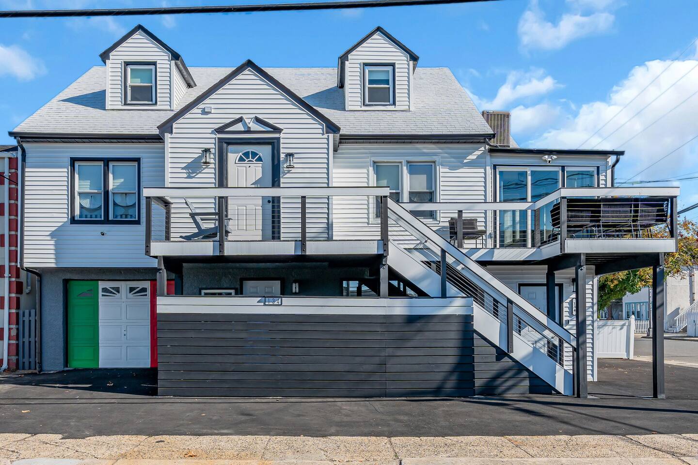 Beach house at the Jersey Shore with modern design, balcony, and colorful garage door, highlighting vacation rental potential.