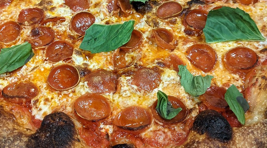 Pepperoni pizza topped with fresh basil leaves, highlighting the delicious offerings at Rosie’s Pizza in Point Pleasant Beach.