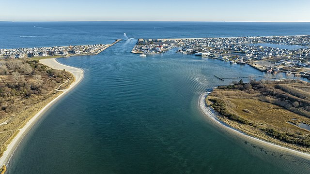 Aerial view of Manasquan Inlet showcasing coastal homes, sandy beaches, and the serene waterway leading to the Atlantic Ocean.