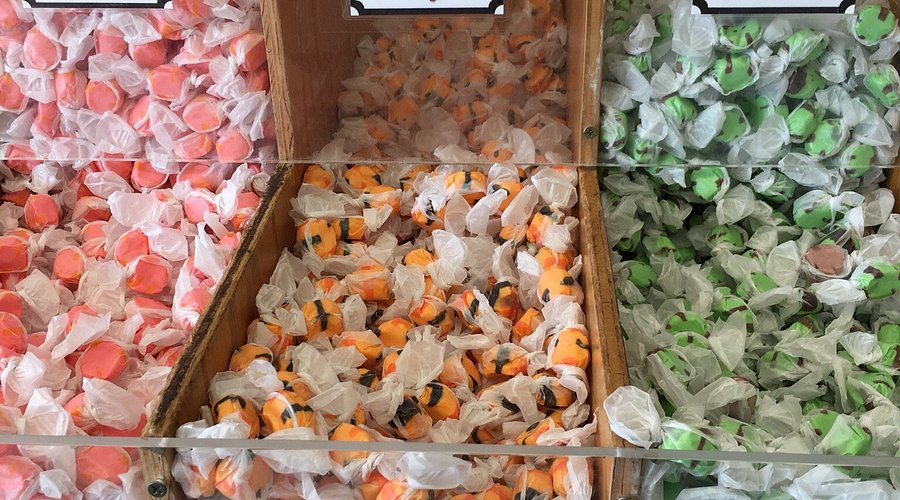 Colorful saltwater taffy in clear bins, showcasing pink, orange, and green varieties, representing a classic Jersey Shore treat.