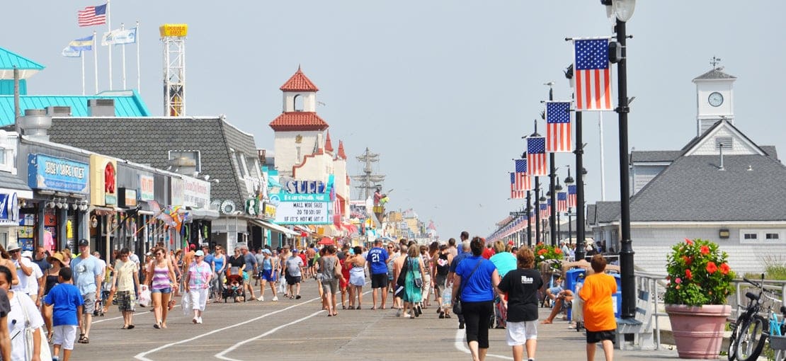 Ocean City boardwalk scene with American flags and crowds of people.