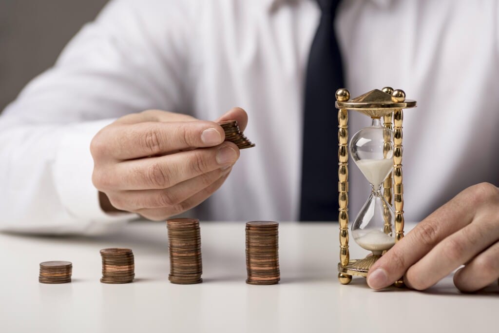 Businessman managing coins and hourglass, symbolizing financial planning and time management in vacation rental investments.