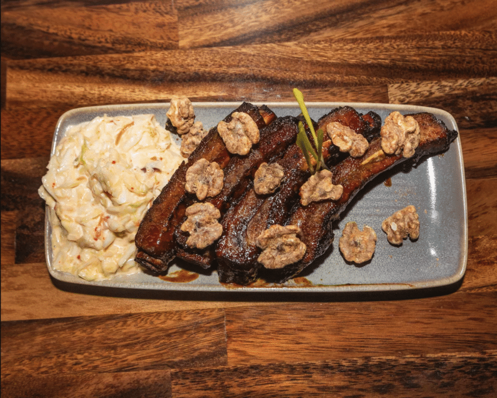 Plate of tender, grilled ribs with a side of creamy coleslaw, served at Berkeley Cut Steakhouse in Seaside Park, NJ, highlighting local steakhouse charm and quality dining experience.