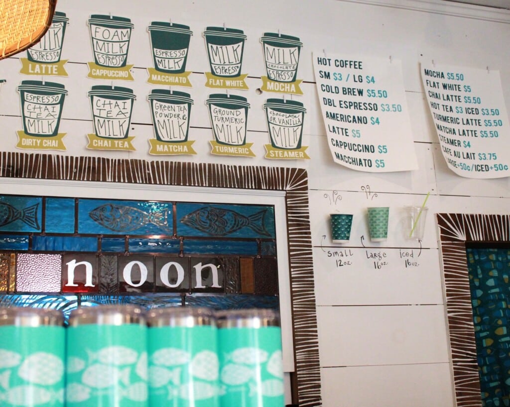 Coffee shop menu display featuring drinks like lattes, cappuccinos, and chai tea at Noon, a creative coffee hub in Seaside Heights, with turquoise cups and a vibrant decor.