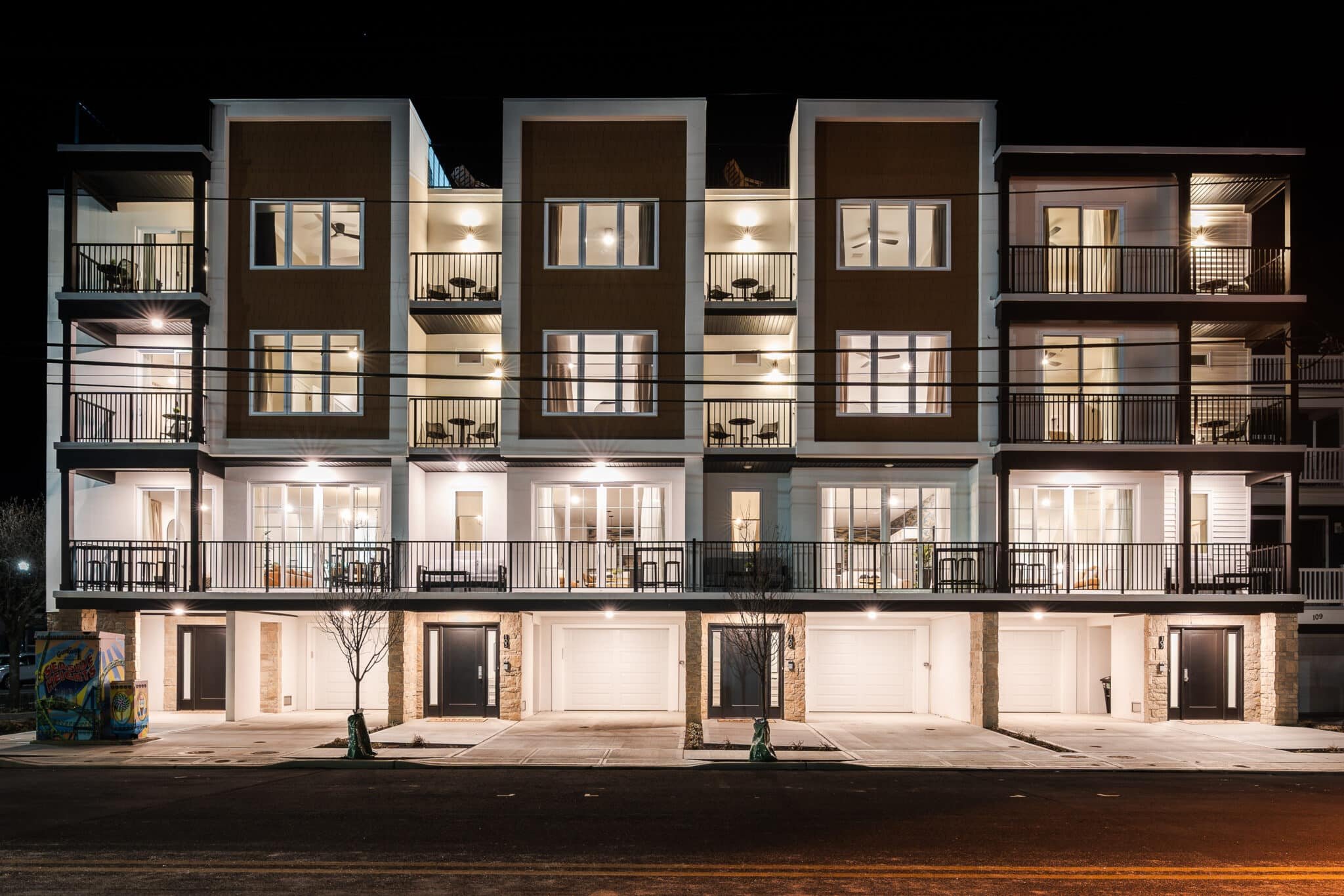 Modern vacation rental property at night with multiple balconies, large windows, and outdoor seating, ideal for families and groups at the Jersey Shore.