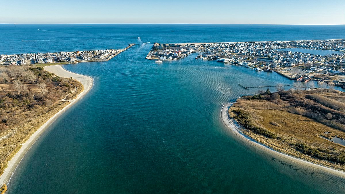 Aerial view of Manasquan Inlet showcasing the waterway, sandy shores, and coastal homes.