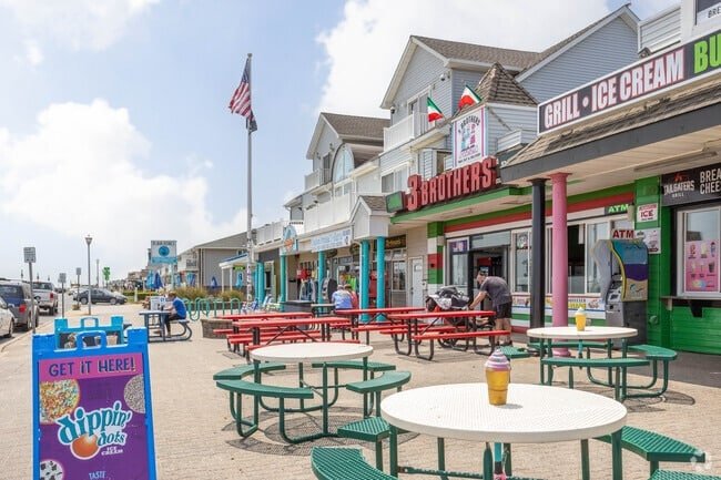 Outdoor dining area in Belmar, NJ, featuring colorful tables and umbrellas, with nearby restaurants.