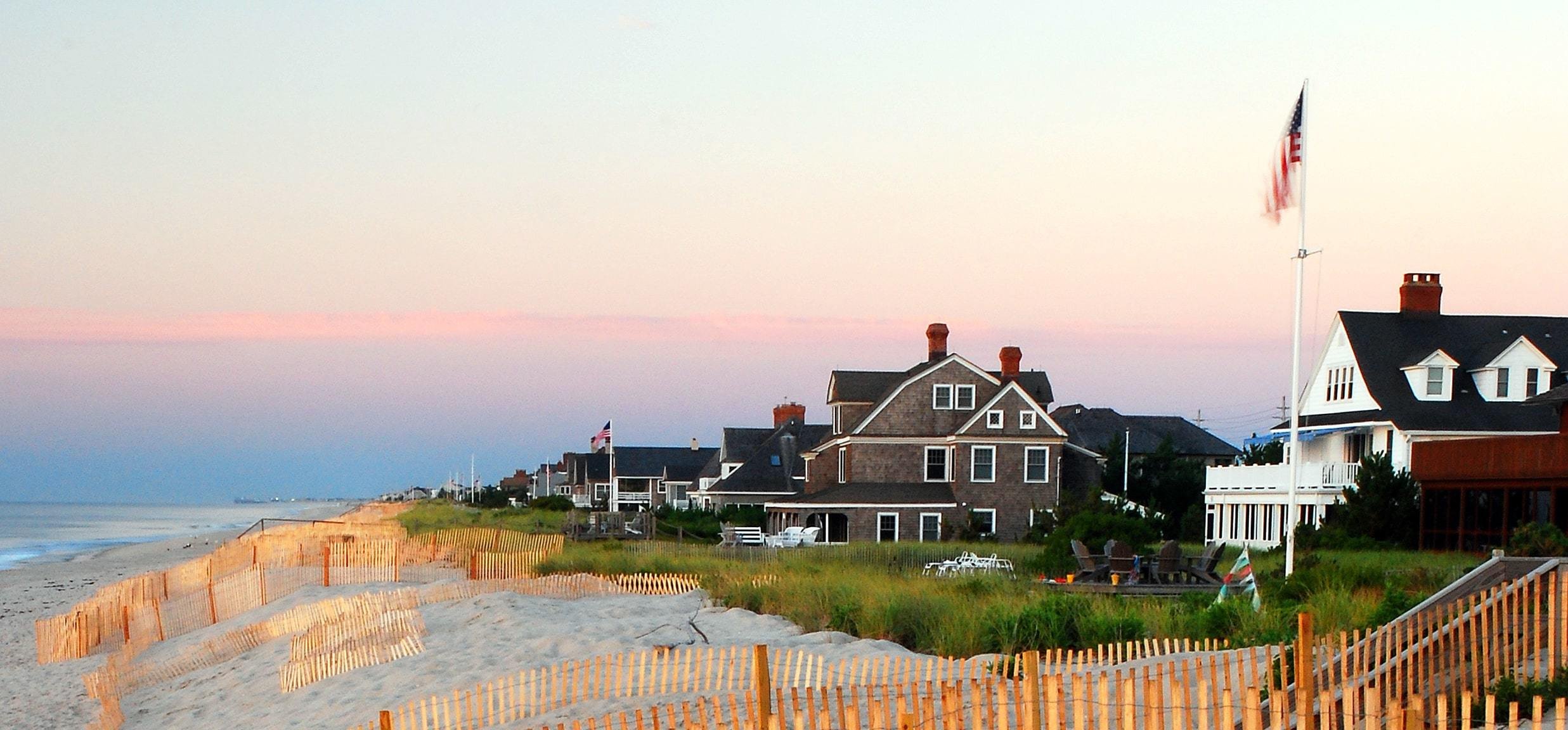 Luxury beachfront homes in Mantoloking, New Jersey, with sandy dunes and a serene evening sky.
