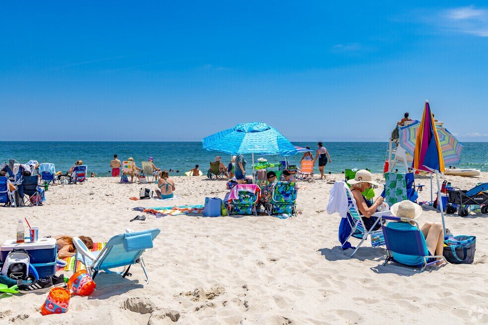 Beach scene in Seaside Park, NJ, with colorful umbrellas and people enjoying the ocean.