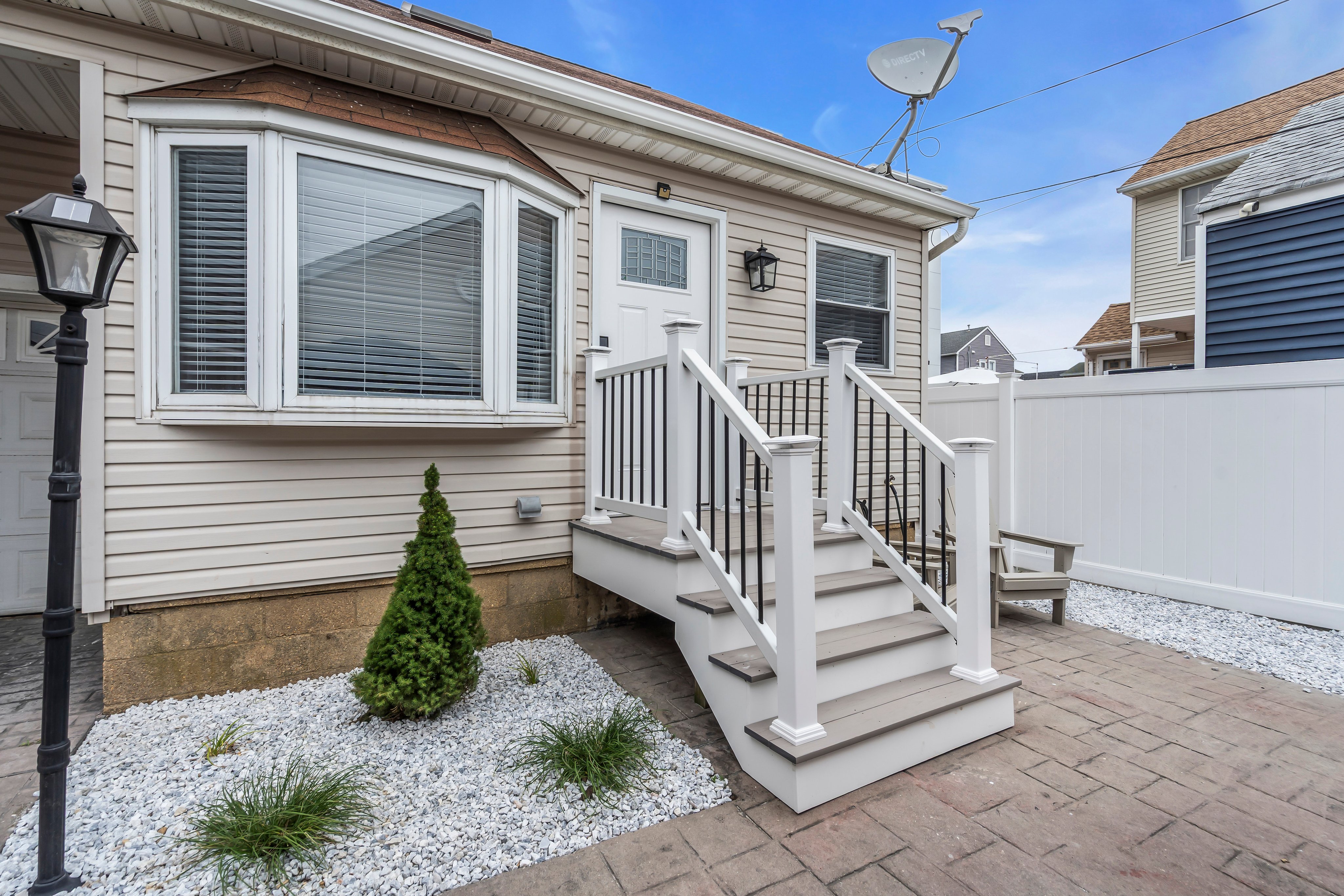 Cozy exterior of a vacation rental home at the Jersey Shore, featuring a white staircase, decorative landscaping, and a welcoming entrance.