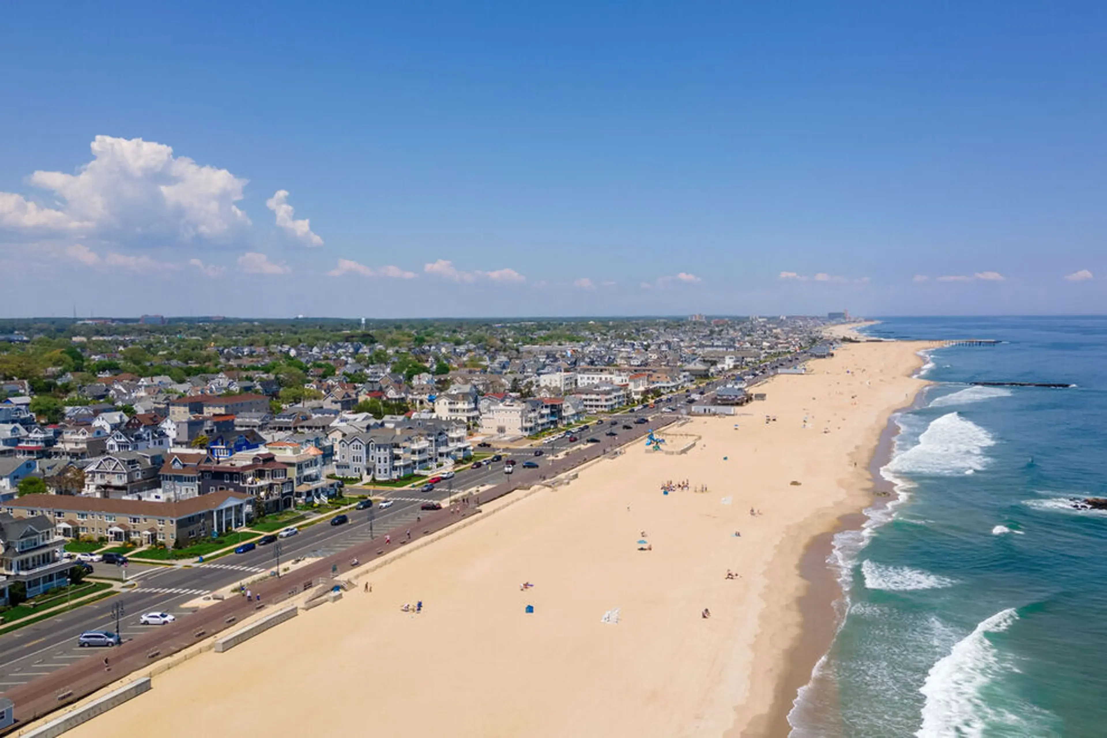 Aerial view of Jersey Shore beach with sandy shoreline, residential homes, and ocean waves.