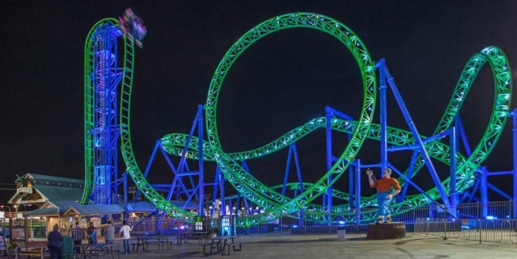 Roller coaster at night with vibrant green and blue lights at Casino Pier.