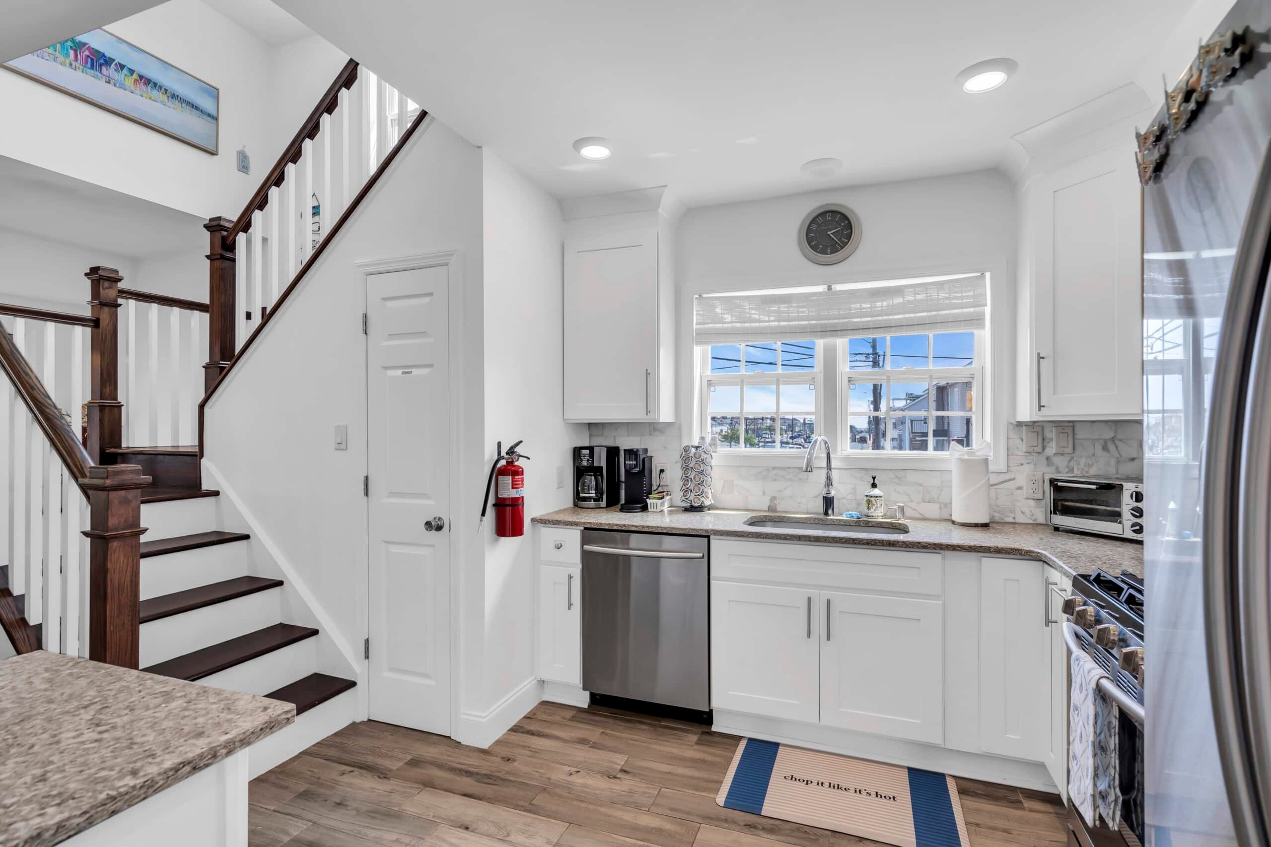 Modern kitchen interior with stainless steel appliances, white cabinetry, and a view of the Jersey Shore through large windows.