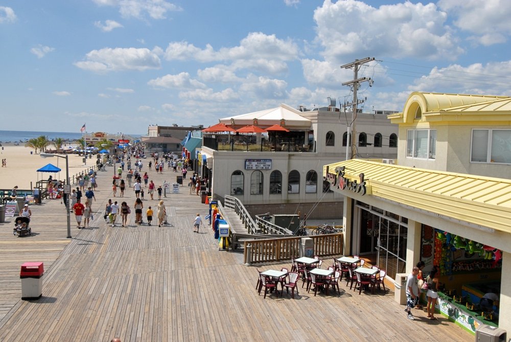 Boardwalk at Point Pleasant Beach bustling with visitors, beachfront access, dining options, and vibrant atmosphere.