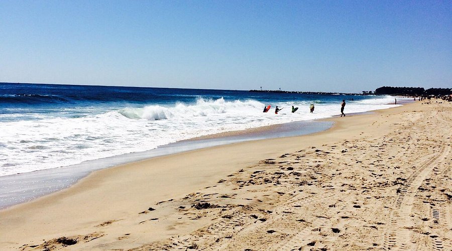 Beautiful Jersey Shore beach scene with gentle waves, surfers enjoying the surf, and a sandy shoreline.