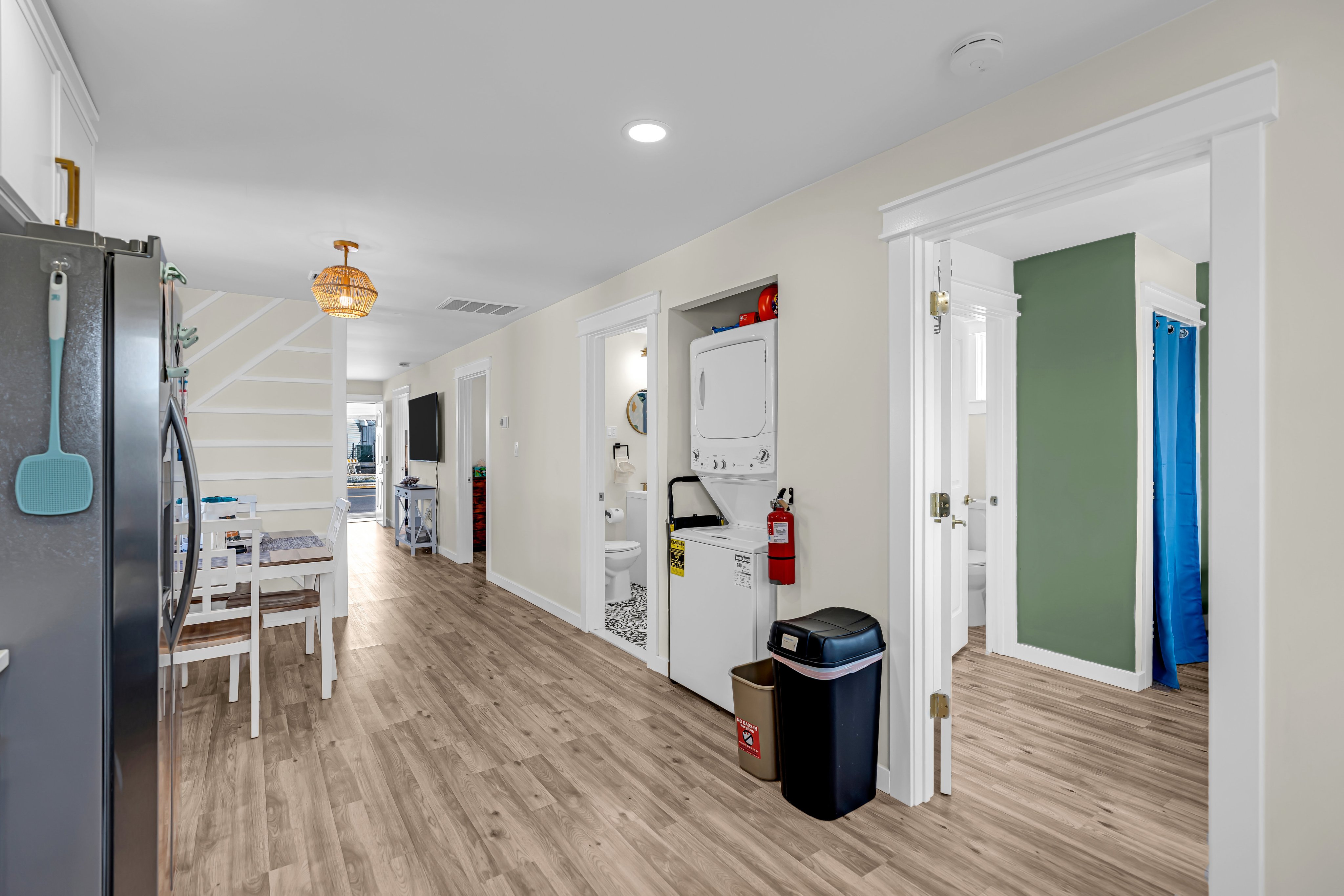 Interior view of a coastal vacation rental, featuring a kitchen area with stainless steel appliances, a dining table, laundry facilities, and a living space.