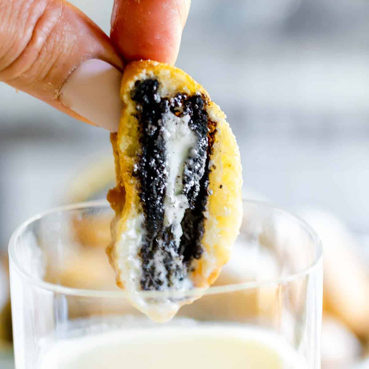 Fried Oreo being dipped into a glass of milk, showcasing the warm, gooey center and crispy outer layer, a popular boardwalk treat at the Jersey Shore.