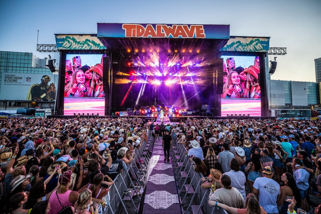 Crowd enjoying live music at Tidal Wave concert, vibrant stage lights, large screens, and festive atmosphere at Jersey Shore summer event.