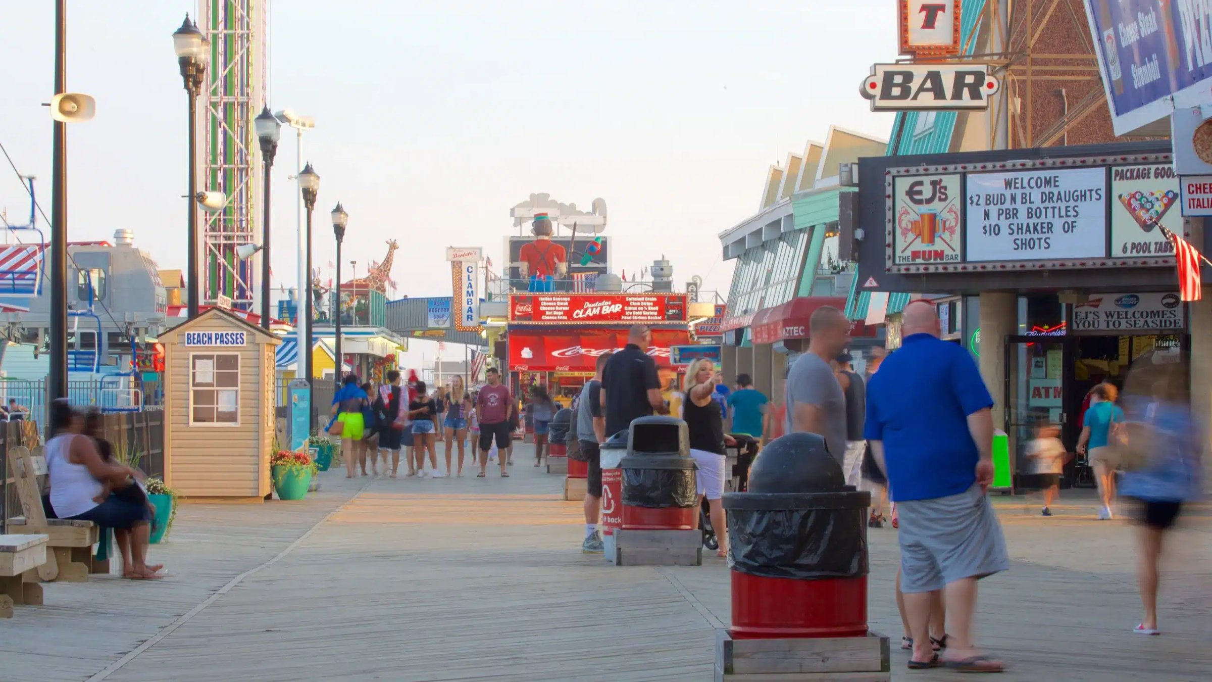Boardwalk scene at Seaside Heights featuring beach pass booth, vibrant shops, and crowds enjoying the Jersey Shore atmosphere, highlighting vacation rentals and local attractions.