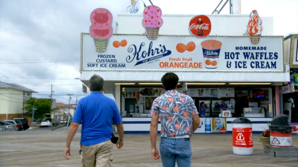 Kohr's Frozen Custard stand at the Jersey Shore featuring colorful ice cream cones, signage for frozen custard and orangeade, and two men walking towards the shop.