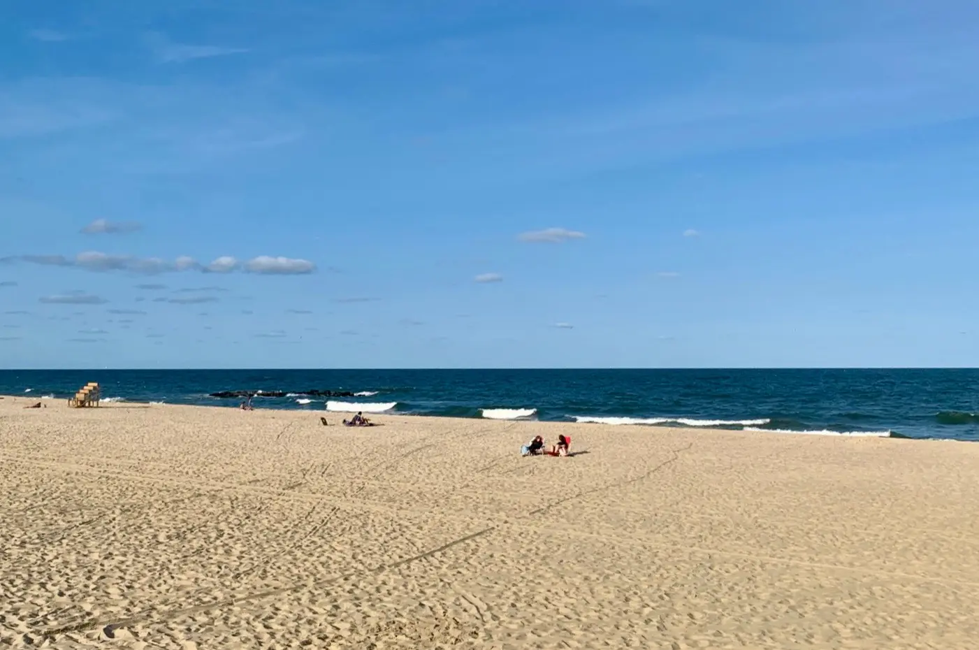 Peaceful beach scene at Lake Como, NJ, featuring clean sand, gentle waves, and a few visitors enjoying a quiet day by the ocean.