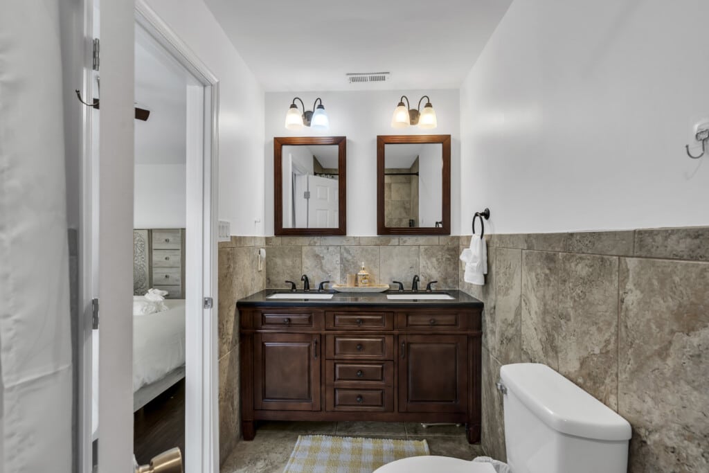 Modern bathroom with dual sinks, wooden vanity, and tiled walls, illustrating vacation rental amenities for Jersey Shore properties.