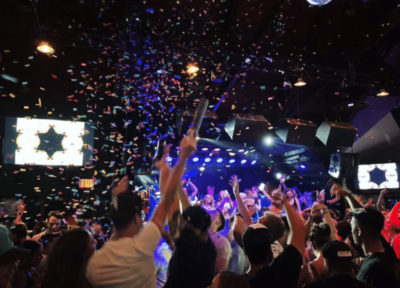 Crowd celebrating at D’Jais bar in Belmar, with confetti falling and vibrant lights, capturing the energetic nightlife atmosphere of the Jersey Shore.