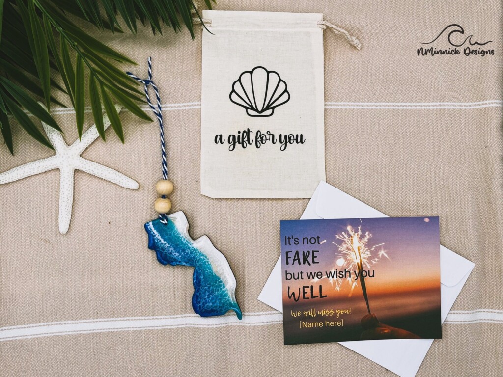 Handcrafted beach-themed gifts including a decorative shell bag, a blue resin state-shaped ornament, and a farewell card with a sparkler, symbolizing Jersey Shore souvenirs and local artisan craftsmanship.