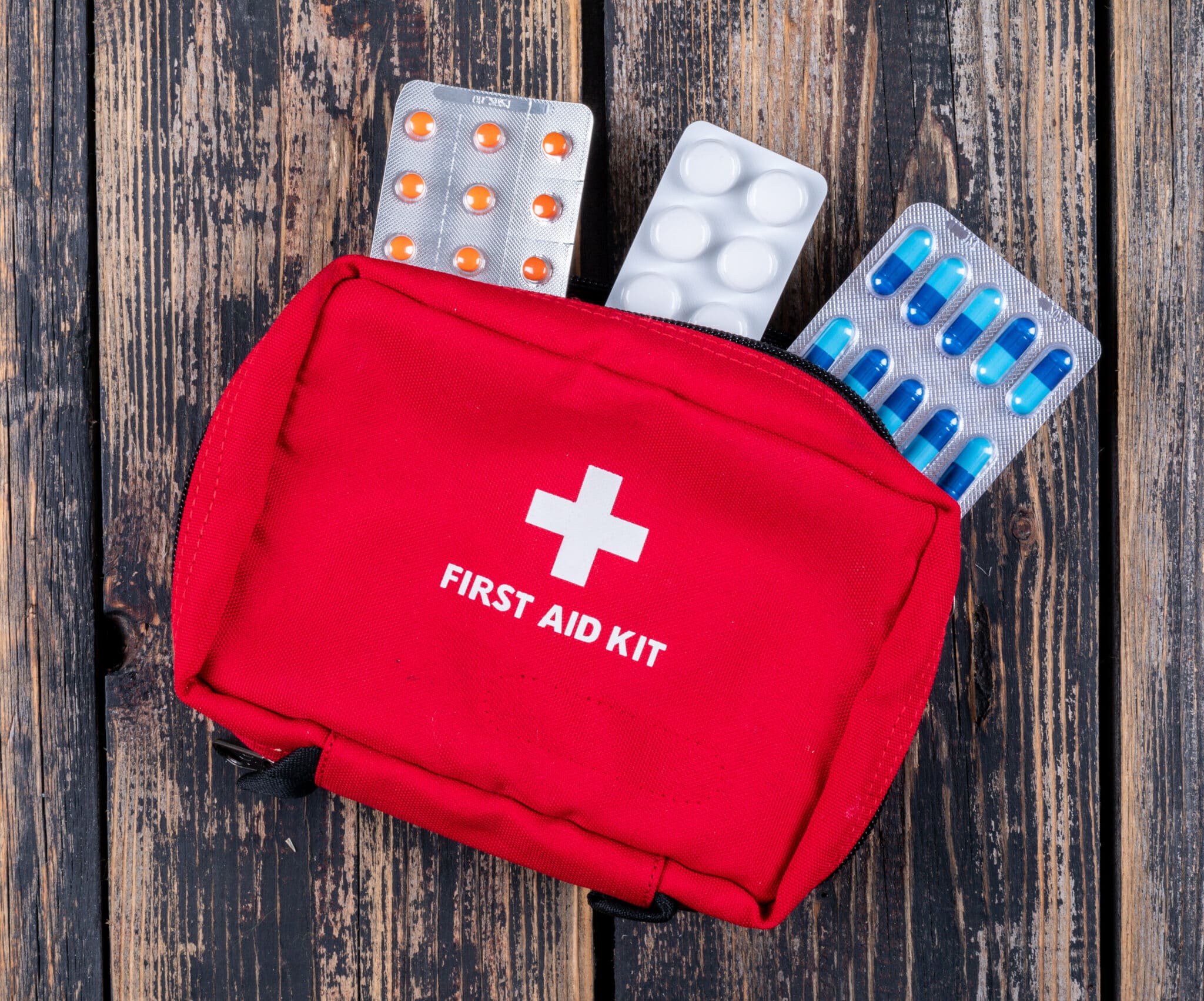 First aid kit with red bag and assorted pills, emphasizing essential safety items for beach vacations and family travel.