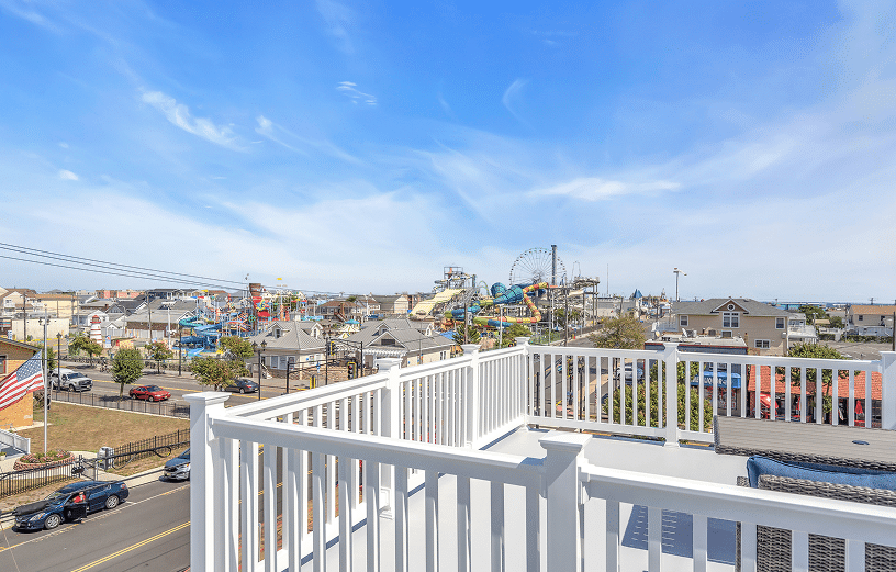 View from a vacation rental rooftop overlooking the Jersey Shore, featuring amusement park attractions, beach houses, and a clear blue sky, emphasizing the competitive vacation rental market.