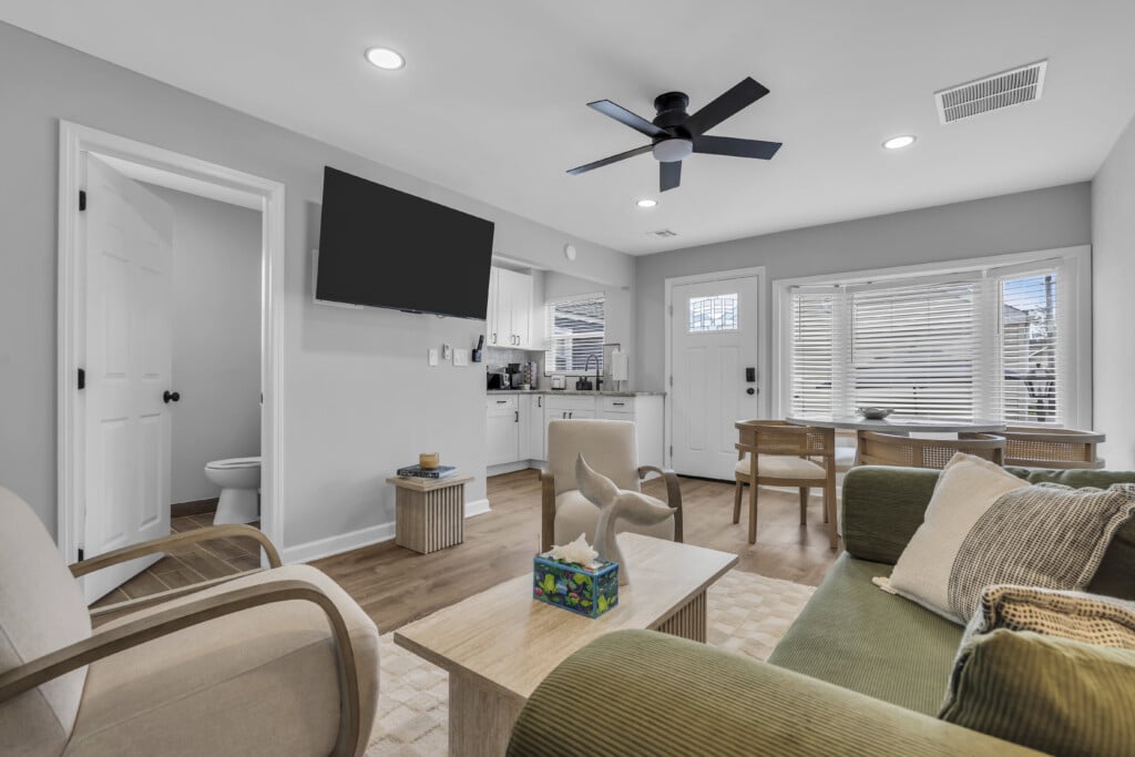 Cozy living area of a vacation rental featuring modern furnishings, a large flat-screen TV, and a dining table, emphasizing comfort and relaxation for Jersey Shore vacations.