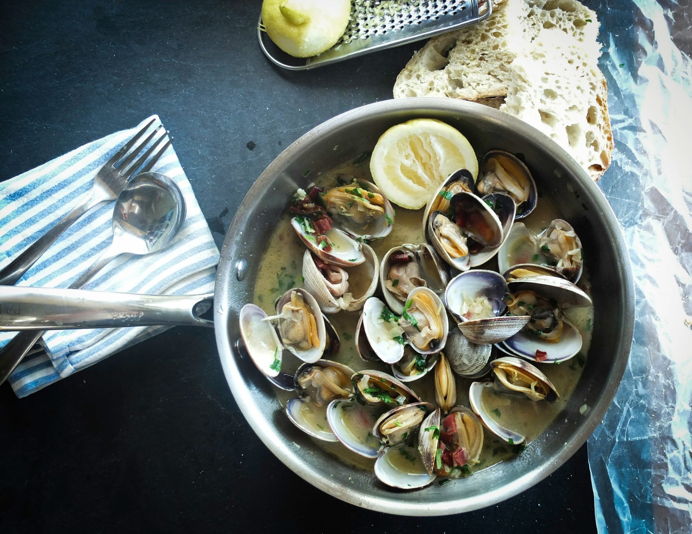 Seafood dish featuring clams in broth with lemon, parsley, and bread, representing Jersey Shore culinary delights.
